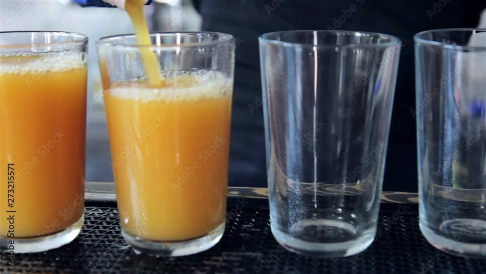 The bartender pours tomato and orange juice into glasses. The bartender pours tomato and orange juice into glasses.