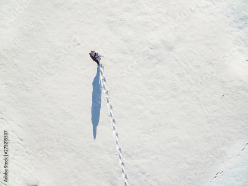 Aerial view of a man walking at fresh snow field.