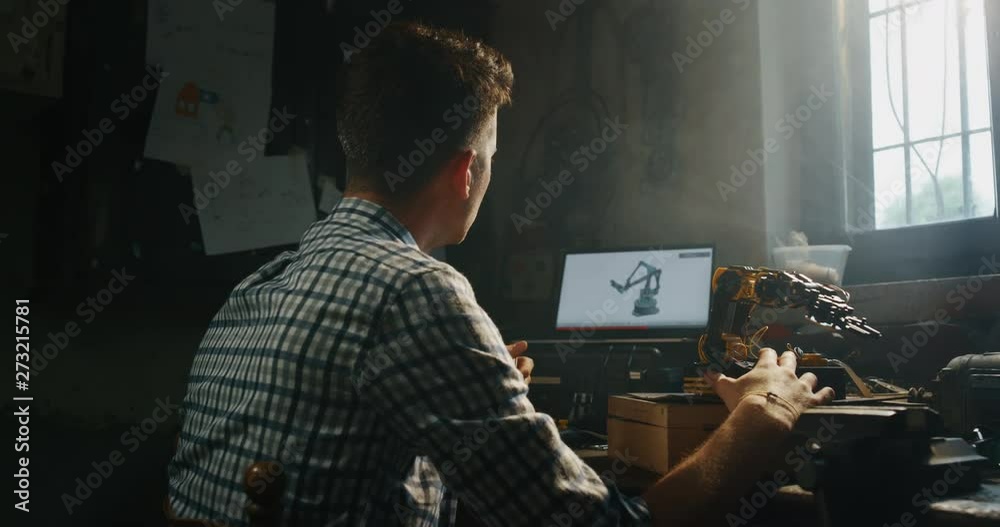 Slow motion of an young professional engineer is working on projection of an innovative technology mechanical arm in his workshop.