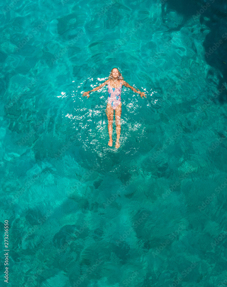Aerial view of a attractive young woman in swimsuit floating in the sea ...