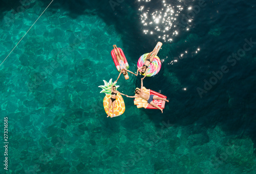 Aerial view of group holding hands on inflatable mattresses on Atokos island, Greece. photo