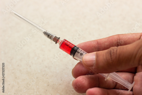 Medical syringe in hands. Medical syringe with red solution. Medical syringe with red solution in hand. Medical syringe with red content