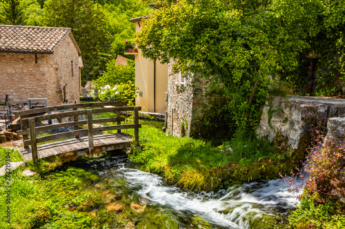 The small village of Rasiglia, crossed by many streams and waterfalls, fed by the Menotre river. A sluice regulates the flow of water. A wooden bridge. Old brick houses. Foligno, Umbria. photo
