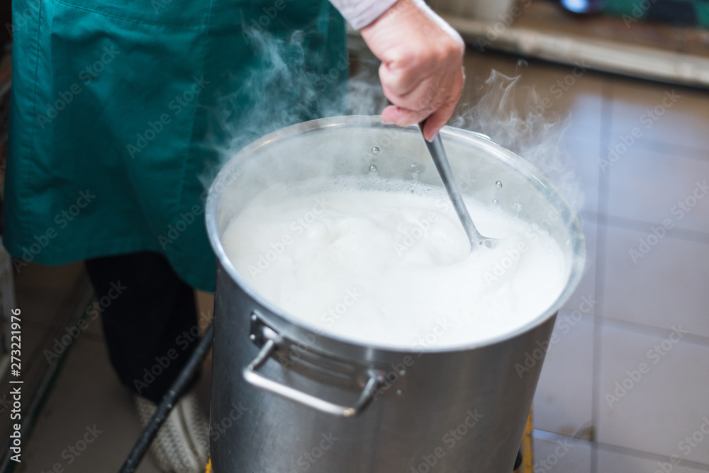A woman cooks milk in a vat and makes cottage cheese and cheese at home. Production of cheese on the farm. A woman cooks milk in a vat and makes cottage cheese and cheese at home. Production of cheese on the farm.