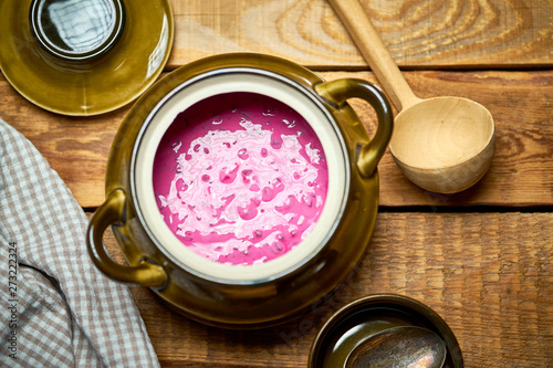 Old vase with  cold beetroot soup and spoon on rustic wooden table photo