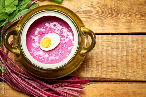 Old vase with cold beetroot soup with egg on rustic wooden table photo