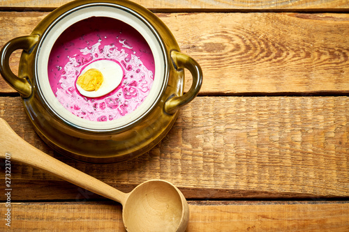 Old vase with  cold beetroot soup and spoon on rustic wooden table photo