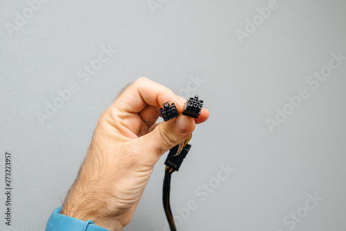 Fotografía Male hand IT worker holding new power adapter cable dongle splitter against gray