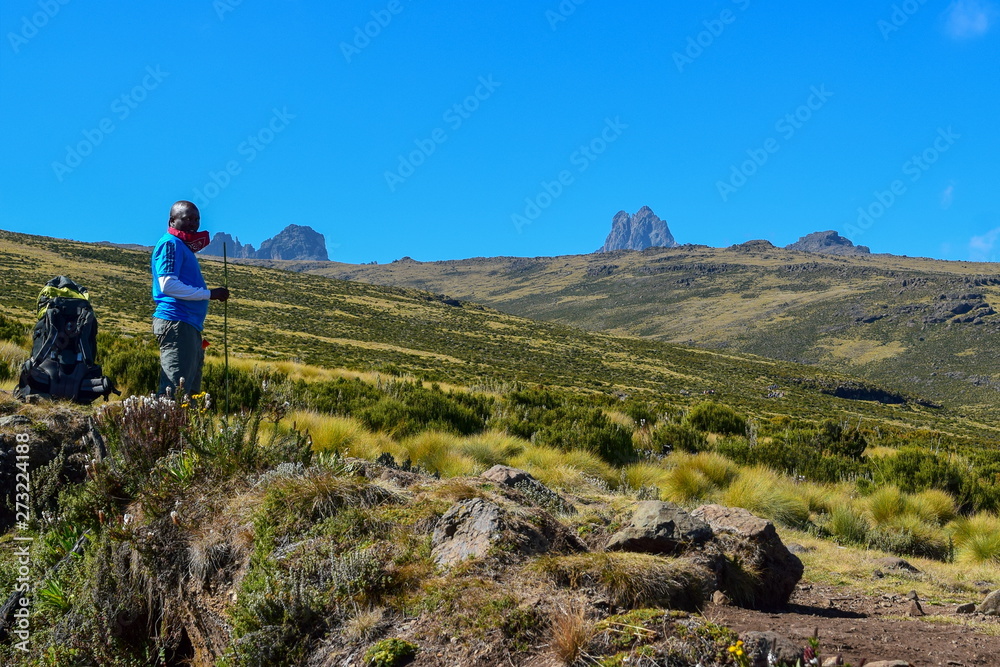 A hiker against a mountain range in the volcanic landscapes of Mount Kenya, Kenya