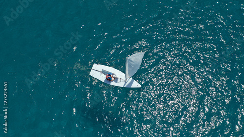 Aerial photo of small sail boat operated by children in exotic tropical bay with turquoise sea © aerial-drone