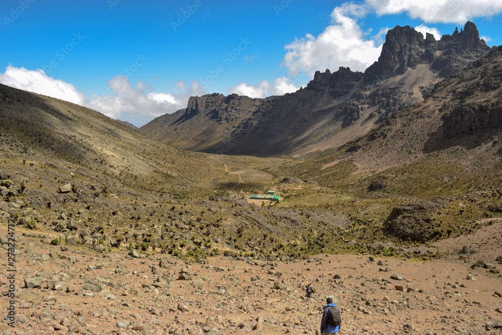 A hiker against a mountain range in the volcanic landscapes of Mount Kenya, Kenya