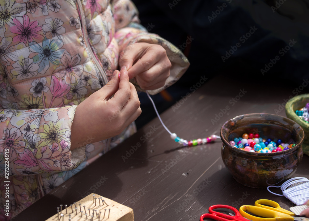 Obraz premium Girl making necklace from beads