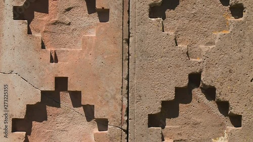Extreme close-up front tilting shot of stone ruins of Pumapunku with precise geometric patterns chiselled on their surfaces, La Paz, Bolivia