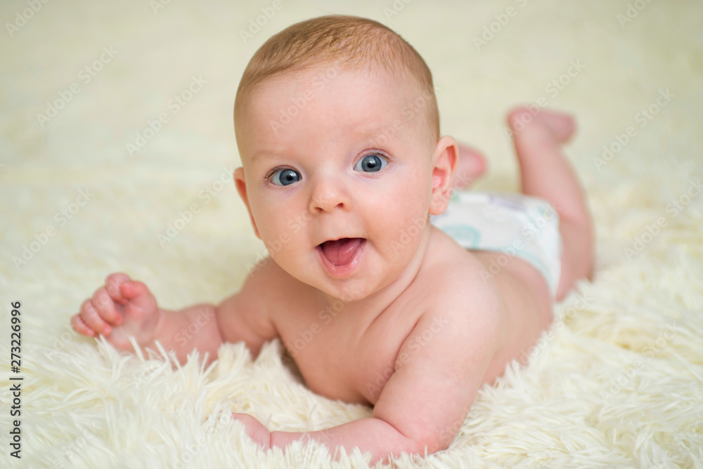 Baby lying down on a soft cozy blanket and looking at camera. Portrait of a cute baby lying down on a blanket Baby lying down on a soft cozy blanket and looking at camera. Portrait of a cute baby lying down on a blanket