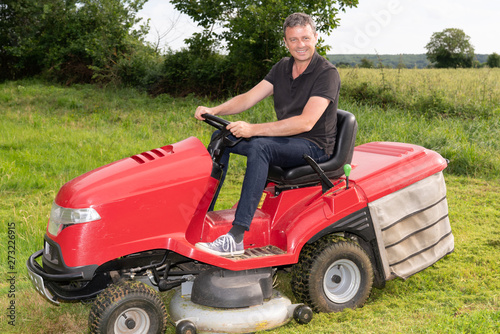 Gardner man on ride-on lawn mower gardener in garden