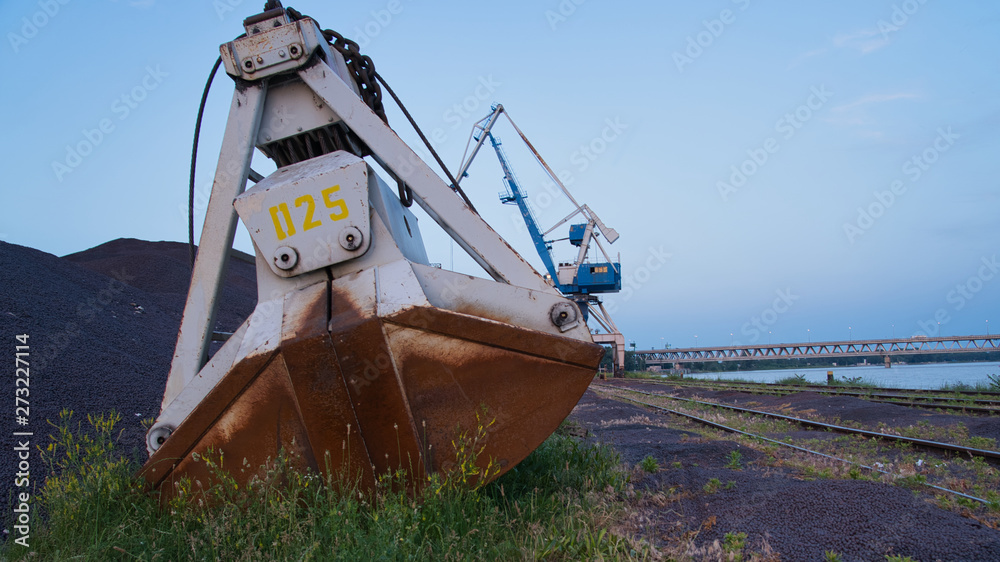Alter Kran und Schaufel bei Sonnenuntergang im Hafen