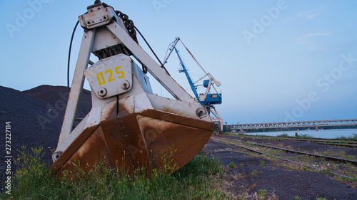 Obraz na płótnie Alter Kran und Schaufel bei Sonnenuntergang im Hafen w salonie