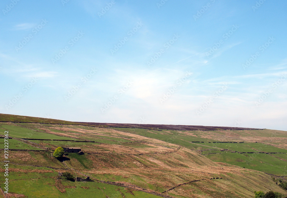 a scenic view of green meadows and stone walls underneath hills and moorland on the old howarth road near pecket well in calderdale west yorkshire