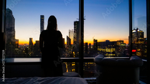 Photography SILHOUETTE: Young woman watches the golden-lit cityscape of New York at dawn