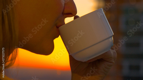 Bild auf Leinwand CLOSE UP: Unrecognizable woman takes a sip of healthy green tea at sunrise
