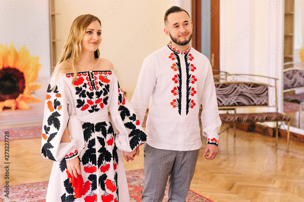 Obraz premium girl and guy in embroidered clothes hold hands in a beautiful ha