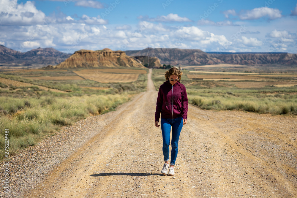 une jeune fille marchant sur une route désertique