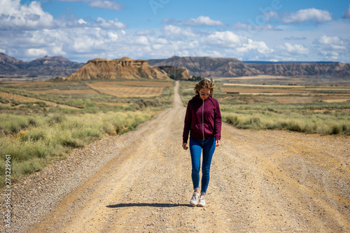 une jeune fille marchant sur une route désertique