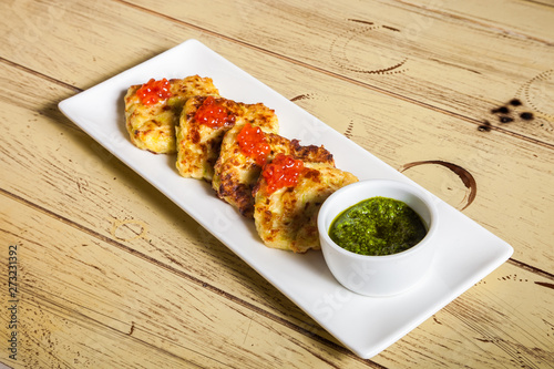 plate with potato pancakes, red caviar and pesto on wooden table