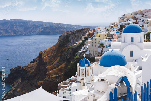Blue domes and bell tower of churches in Oia, Santorini, Greece. The edge of the caldera with the blue domes of churches in the foreground, selective focus