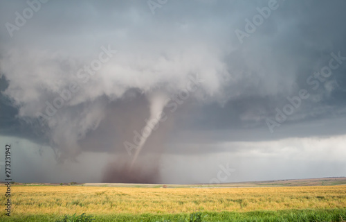 Obraz na plátně A thin cone tornado spins over the open landscape of the Great Plains