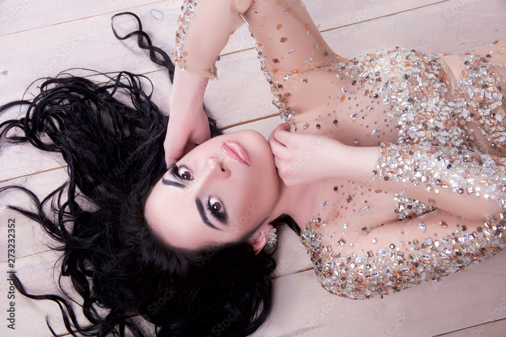 Naklejka premium Gorgeous brunette in a dress with rhinestones in the New Year's interior.