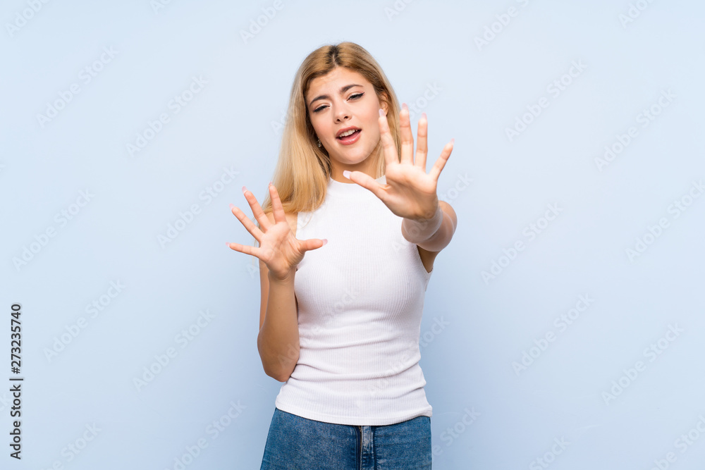 Teenager girl over isolated blue background having doubts while raising hands Teenager girl over isolated blue background having doubts while raising hands
