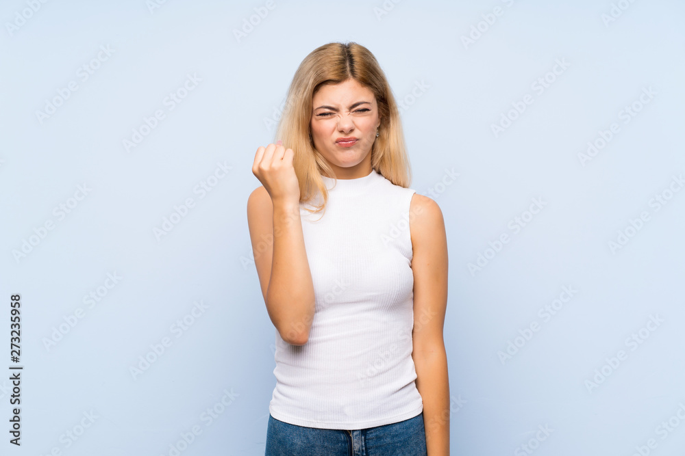 Teenager girl over isolated blue background pointing to the side to present a product Teenager girl over isolated blue background pointing to the side to present a product