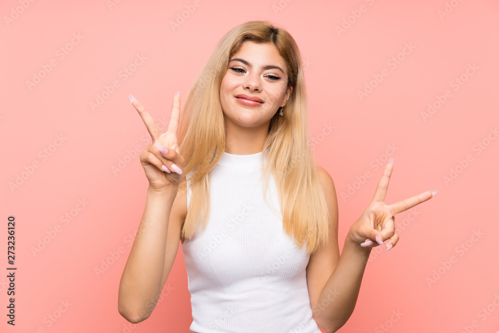 Teenager girl over isolated pink background smiling and showing victory sign Teenager girl over isolated pink background smiling and showing victory sign