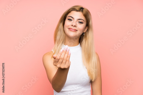 Teenager girl over isolated pink background inviting to come