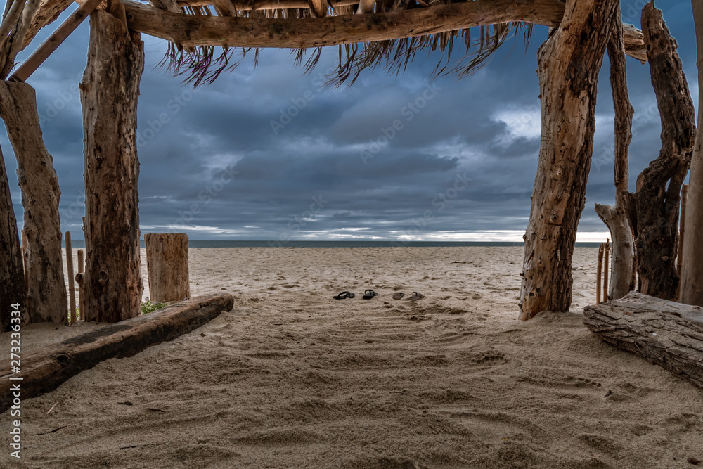 Shipwrecked on a desert island. Looking out at an approaching storm from a homemade shelter made up of driftwood Shipwrecked on a desert island. Looking out at an approaching storm from a homemade shelter made up of driftwood