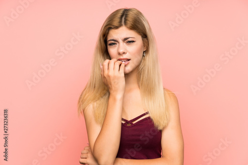 Teenager girl over isolated pink background nervous and scared