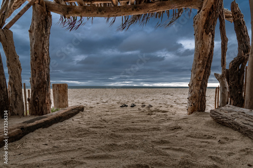 Shipwrecked on a desert island.  Looking out at an approaching storm from a homemade shelter made up of driftwood