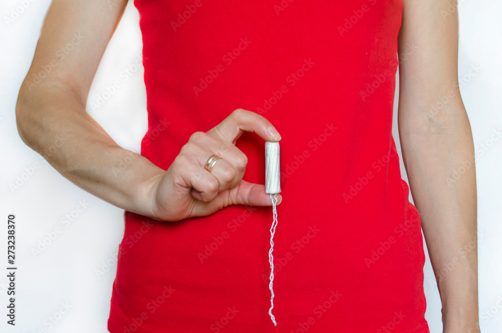 tampon in a female hand. girl holding a tampon. tampon on a red background.  isolated.soft focus. Stock Photo | Adobe Stock