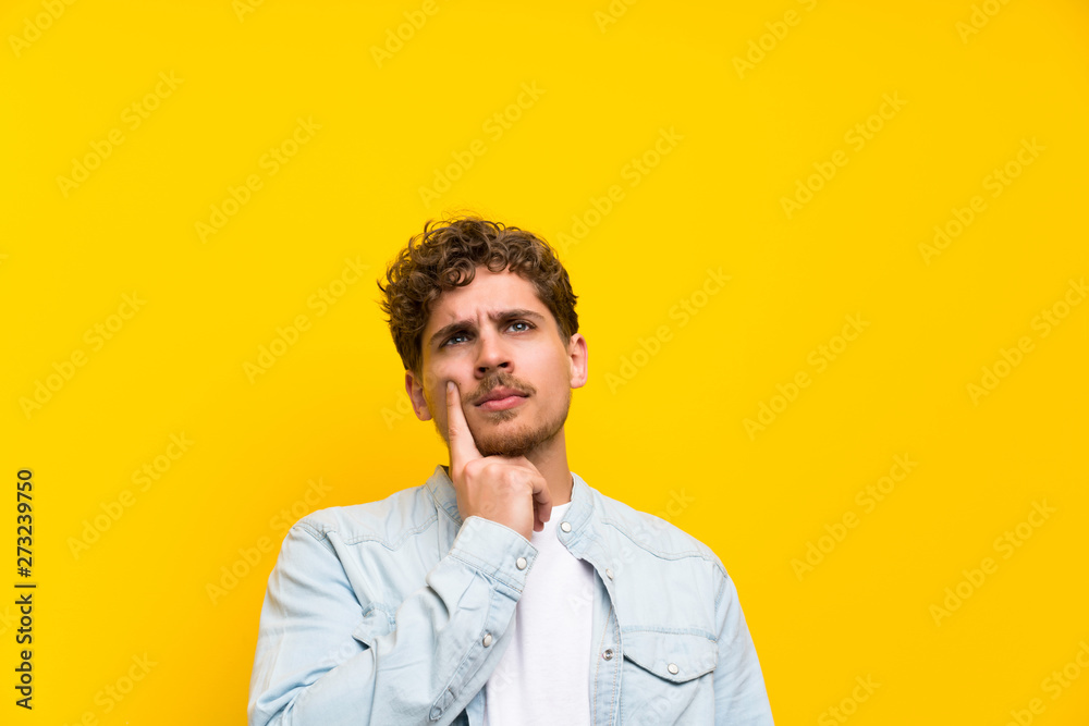 Blonde man over isolated yellow wall thinking an idea Blonde man over isolated yellow wall thinking an idea