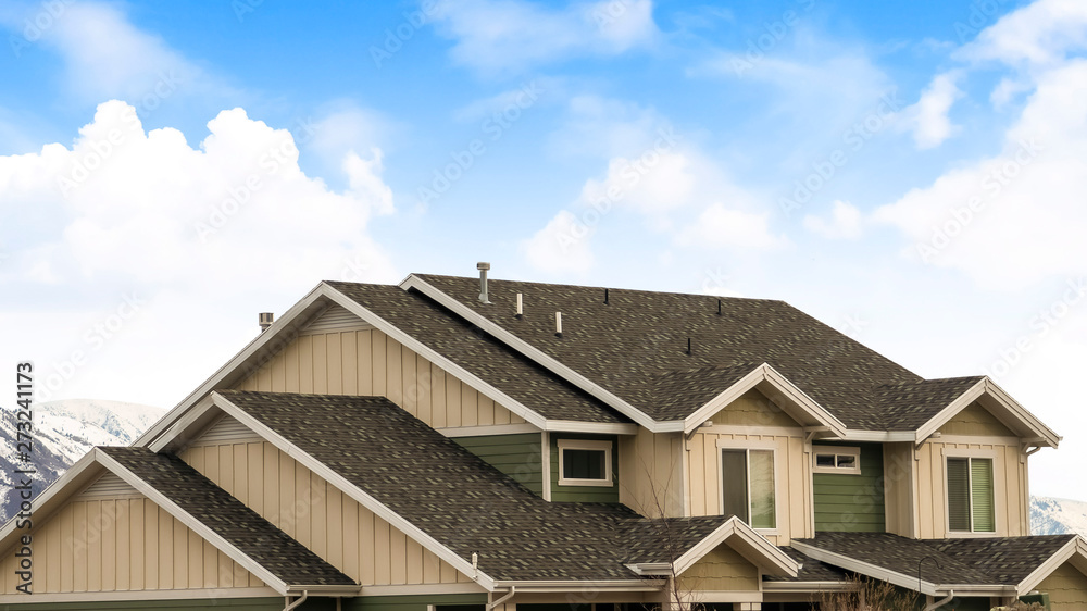 Panorama frame House exterior with view of the dark pitched roof against a cloudy blue sky