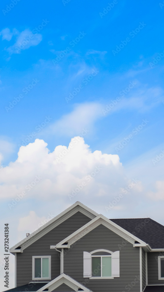 Vertical frame Exterior of the top floor of a house with blue sky and bright clouds background Vertical frame Exterior of the top floor of a house with blue sky and bright clouds background