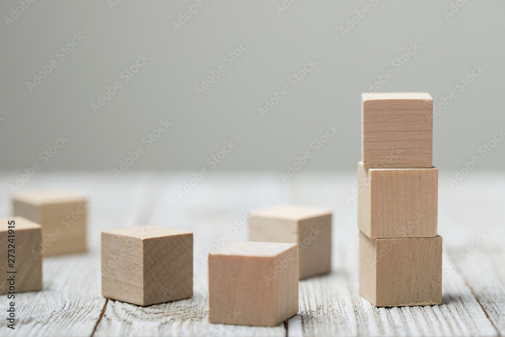 Three wooden toy cubes arranged in vertical on white grey wooden background Three wooden toy cubes arranged in vertical on white grey wooden background