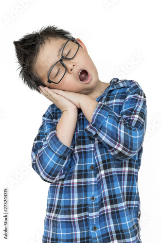 Little child in glasses feels sleepy on isolated white background with blue shirt