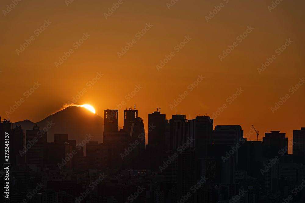 文京区から見た夕焼けの新宿ビル群と富士山に降りる太陽