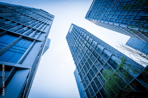 Bottom view of modern skyscrapers in business district against blue sky