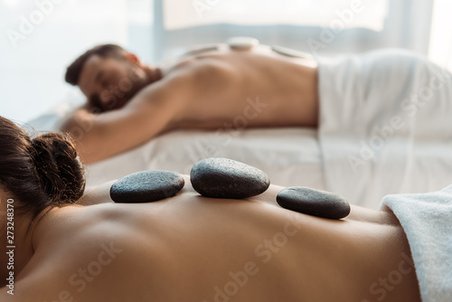 selektywna fokus kobiety o masaż kamieniami w pobliżu mężczyzny w centrum spa