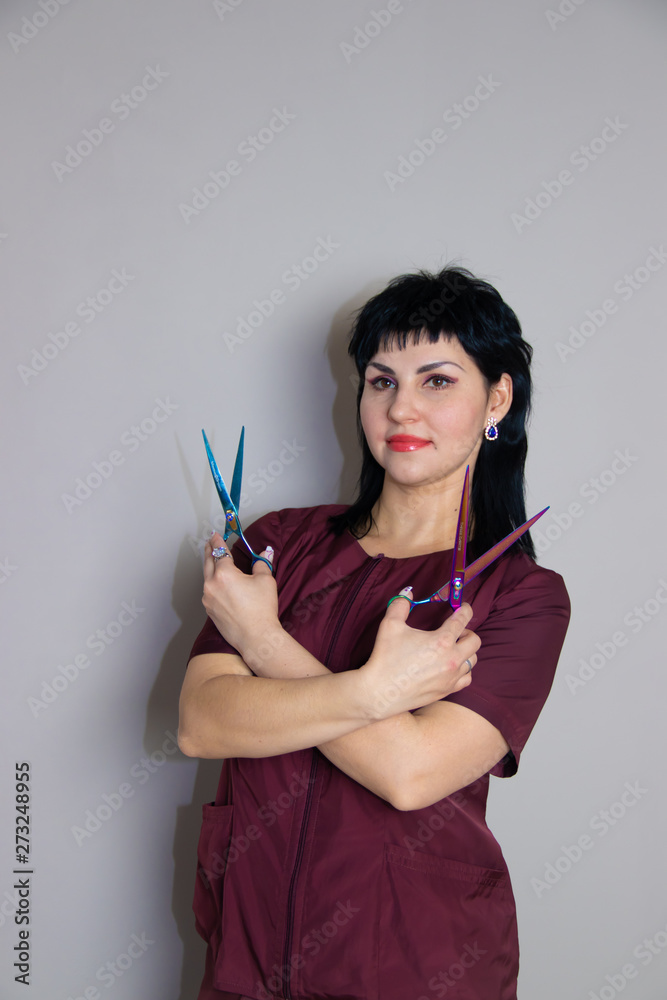 Woman in a suit with scissors on a monochrome gray background. Woman with scissors. Woman in a suit. Woman in a suit with scissors on a monochrome gray background. Woman with scissors. Woman in a suit.