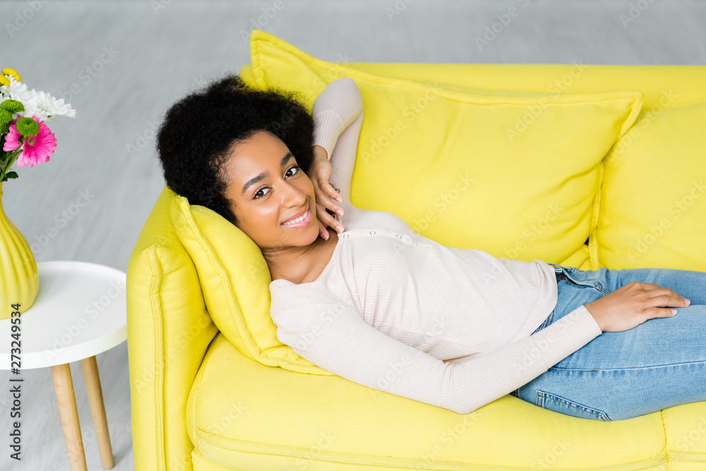 high angle view of african american woman lying on couch and looking at camera high angle view of african american woman lying on couch and looking at camera