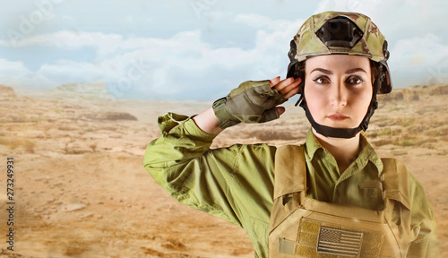 Portrait of young US military soldier woman saluting on desert background with space for text. 